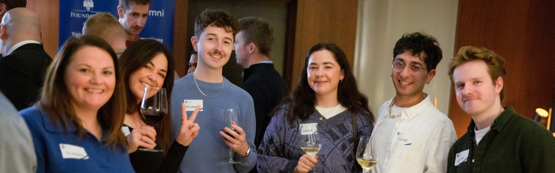 Six alumni at a global event, smiling at the camera.